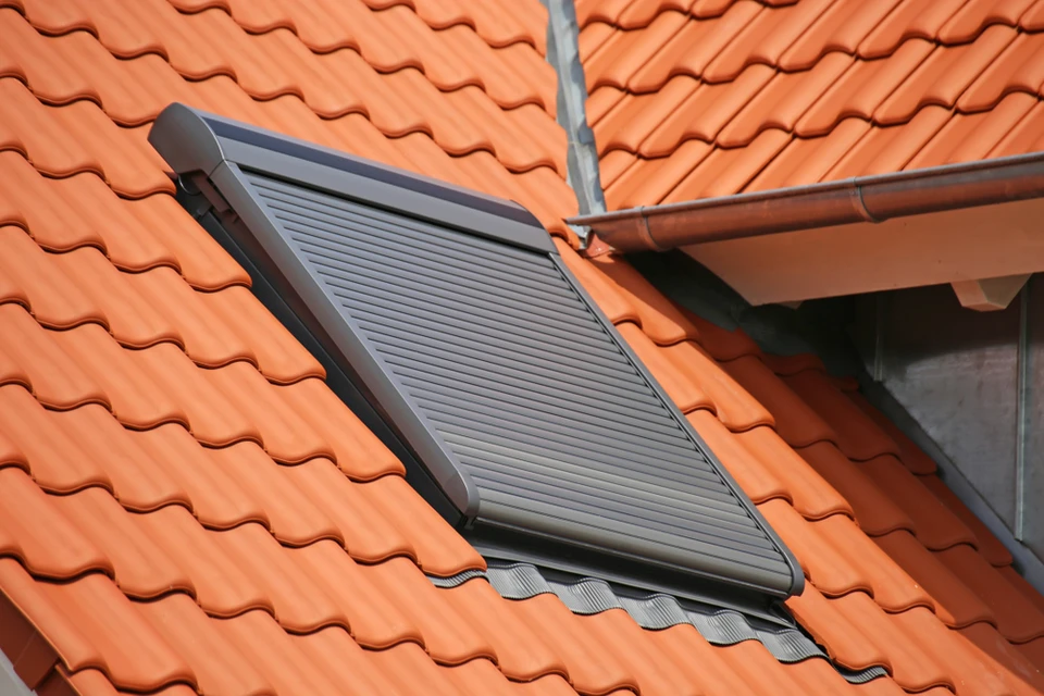 Extérieur, toiture en tuiles terre cuite avec volet roulant solaire gris installé sur lucarne