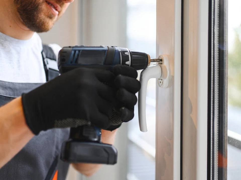 Un bricoleur professionnel répare l'écluse de la porte d'entrée métallique, Un homme réparant l'écluse avec tournevis