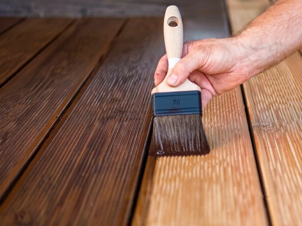 Homme en salopette effectuant des travaux de maintenance sur un volet roulant extérieur sous pergola