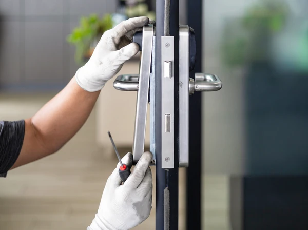 Homme en salopette effectuant des travaux de maintenance sur un volet roulant extérieur sous pergola