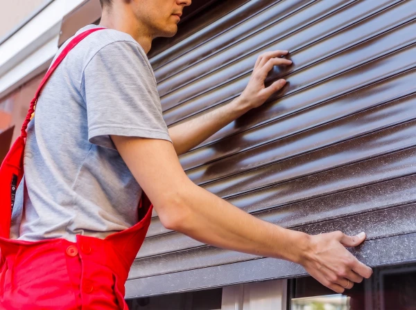 Un technicien en salopette bleue installe ou ajuste une fenêtre à double vitrage dans un intérieur résidentiel moderne